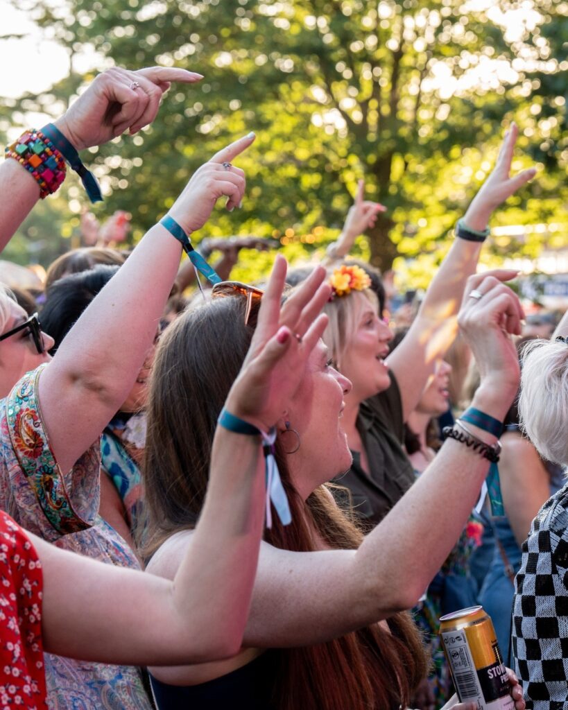 close up, side shot of the crowd, all with their arms in the air.