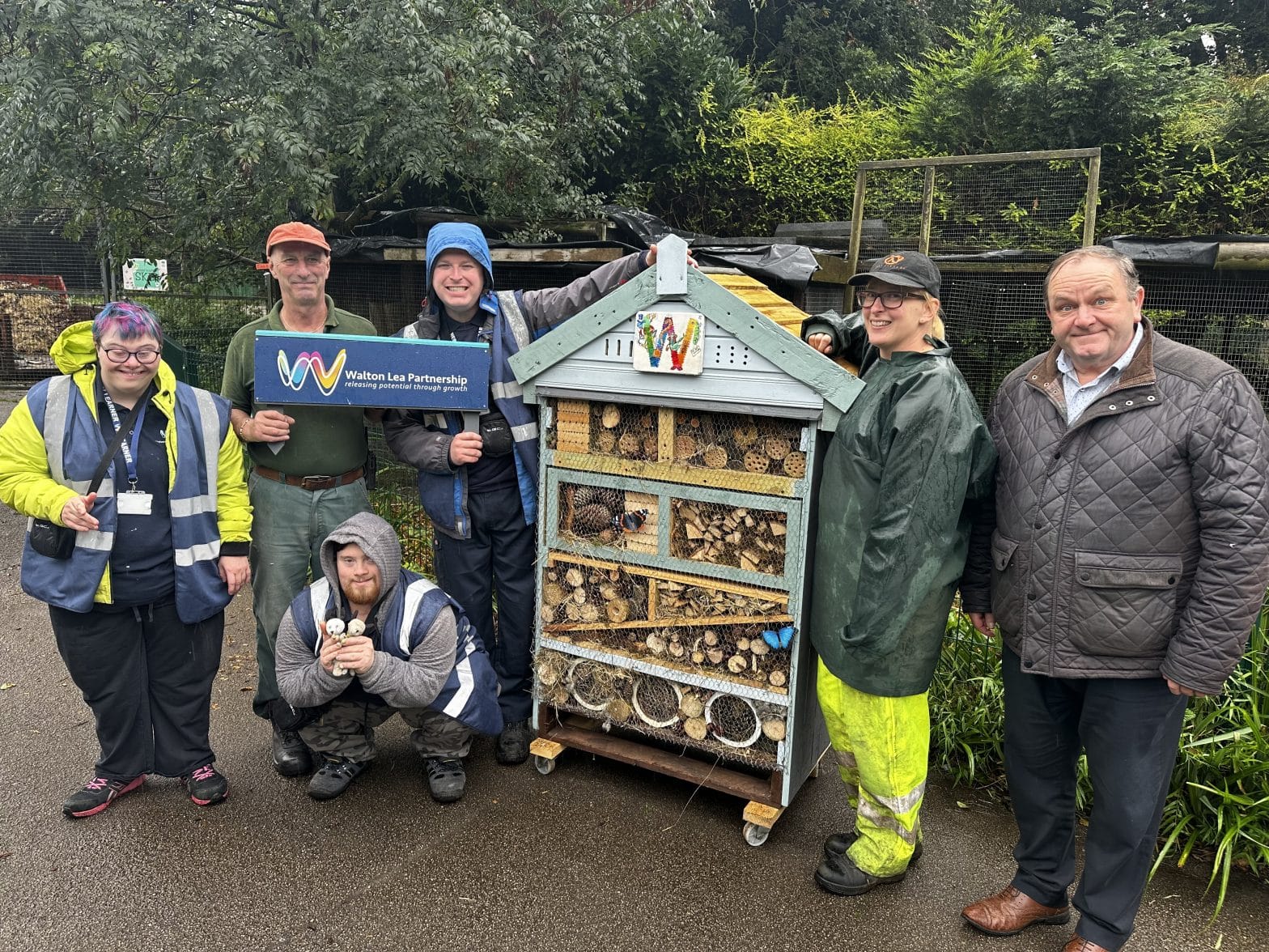 members of the Walton Lea team hand over the bug hotel to the Children's Zoo team.