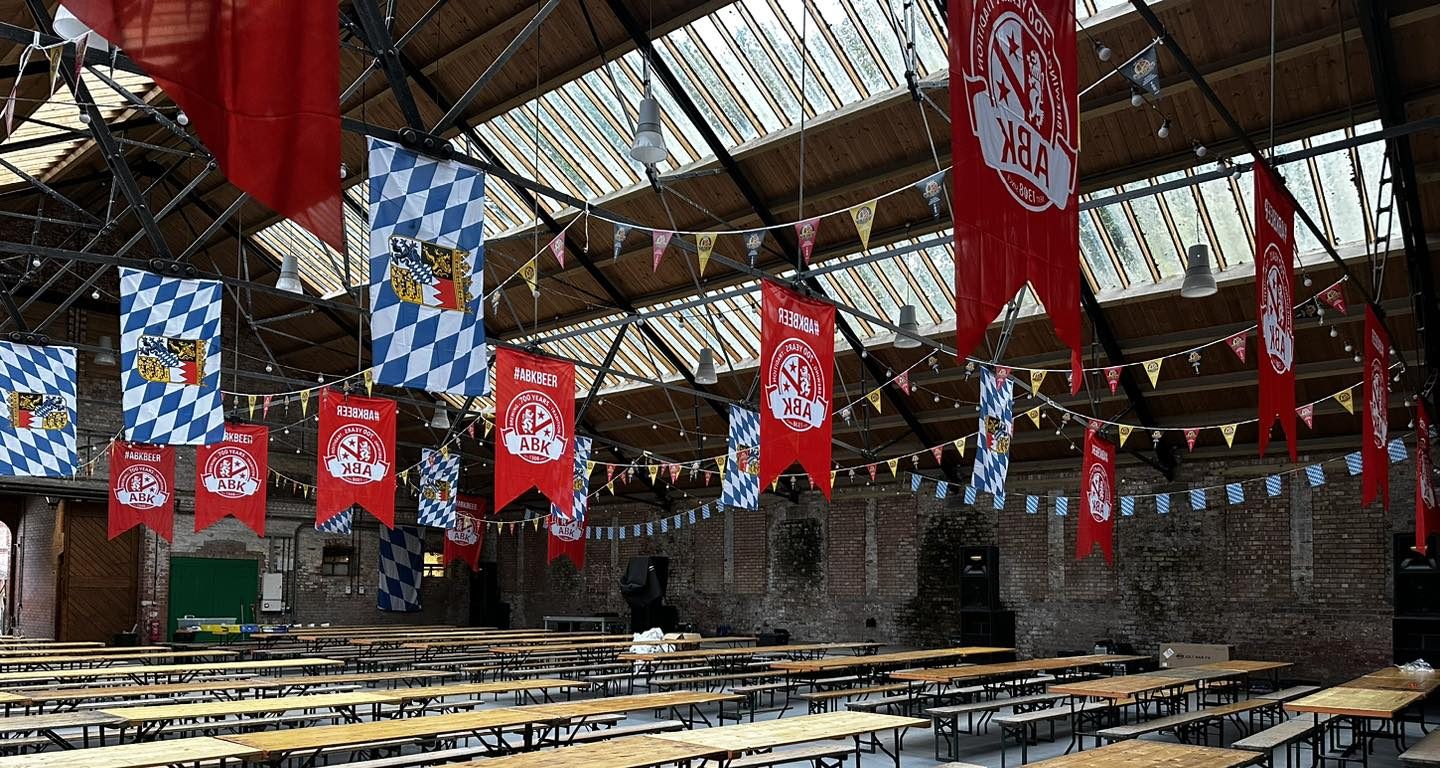 Old Riding school decorated with oktoberfest flags and long benches and tables.