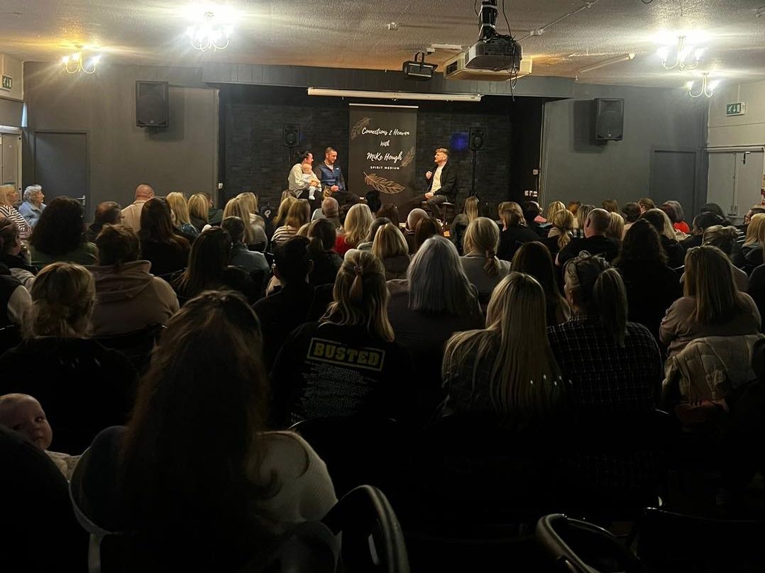 An audience watches Mike Hough during a spiritual reading.