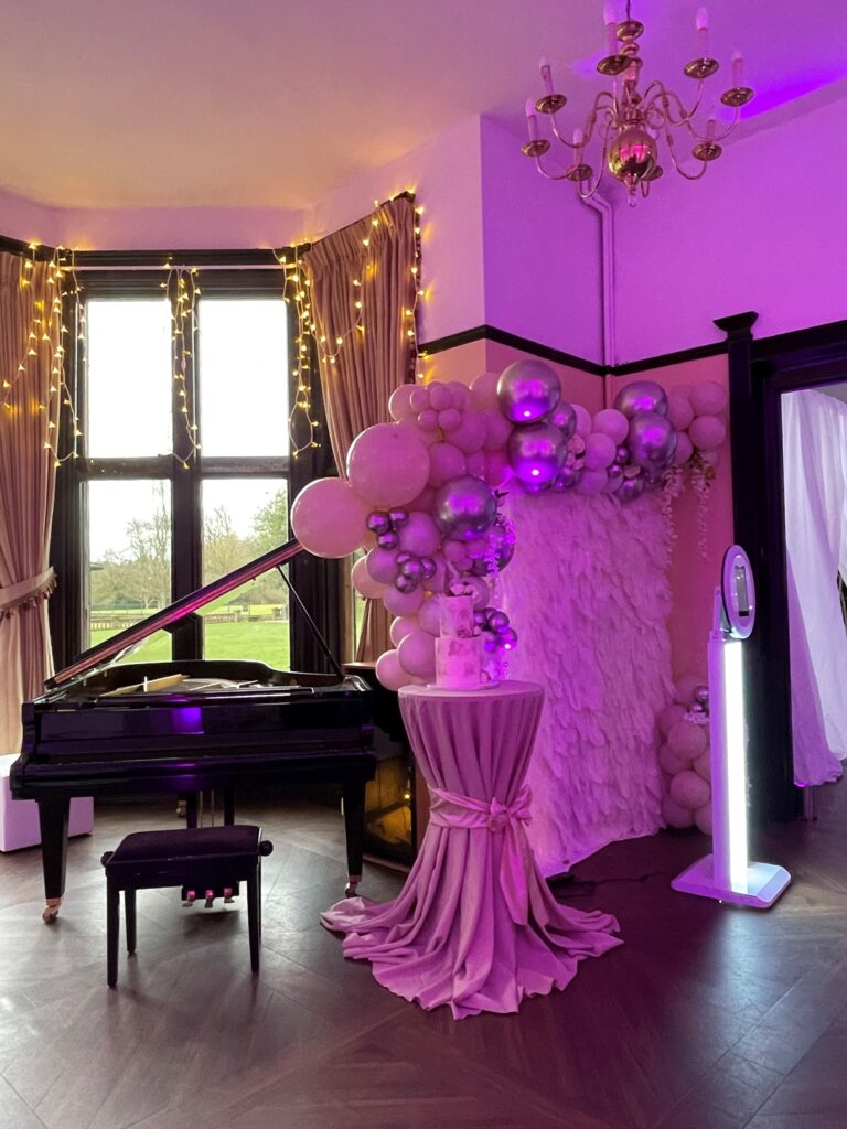 The Concert Room Walton Hall decorated with a tall bar table and balloons near the piano.