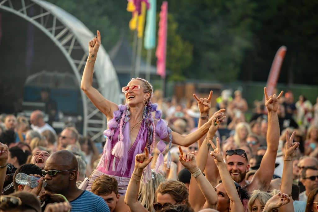 The crowd enjoying the music including one lady on someone's shoulders at Daresbury Festival 2023